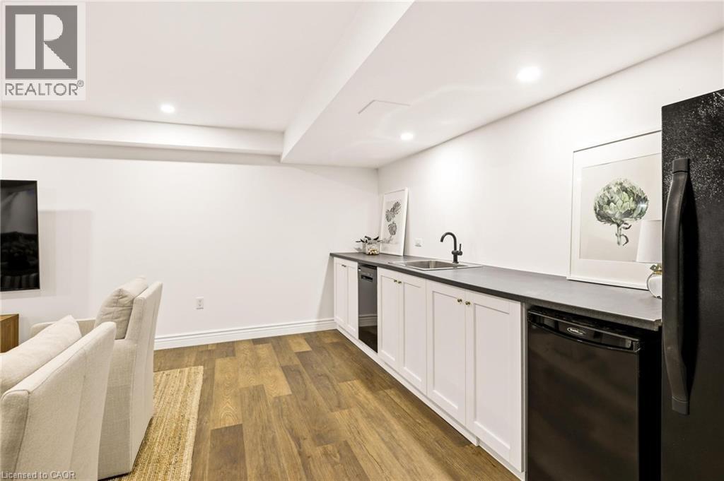 Contemporary wet bar featuring a black sink and faucet, white shaker cabinetry, and dark countertops - 129 Magnificent Way, Binbrook, ON - Indoor