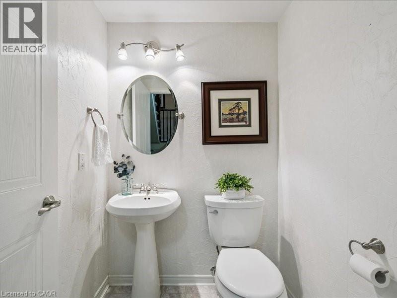 Pedestal sink with a brushed nickel faucet, oval wall mirror, and track lighting - 245 Bishop Street S Unit# 4, Cambridge, ON - Indoor Photo Showing Bathroom