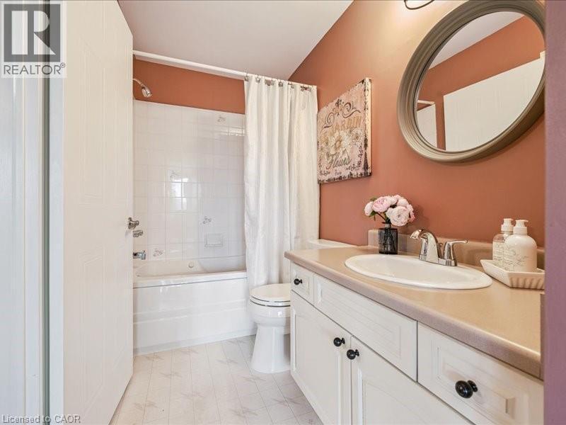 Bathroom featuring a single vanity with an integrated sink, cream-toned countertop, and white cabinetry with dark hardware - 245 Bishop Street S Unit# 4, Cambridge, ON - Indoor Photo Showing Bathroom