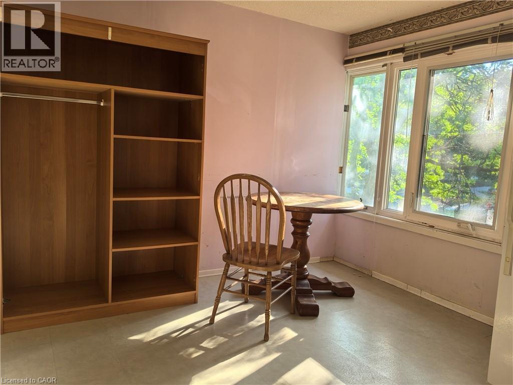 Room featuring light-colored walls and flooring, a multi-pane window, and a built-in wood-finish shelving unit with an integrated wardrobe rod - 134 Greenbrier Drive, Waterloo, ON - Indoor