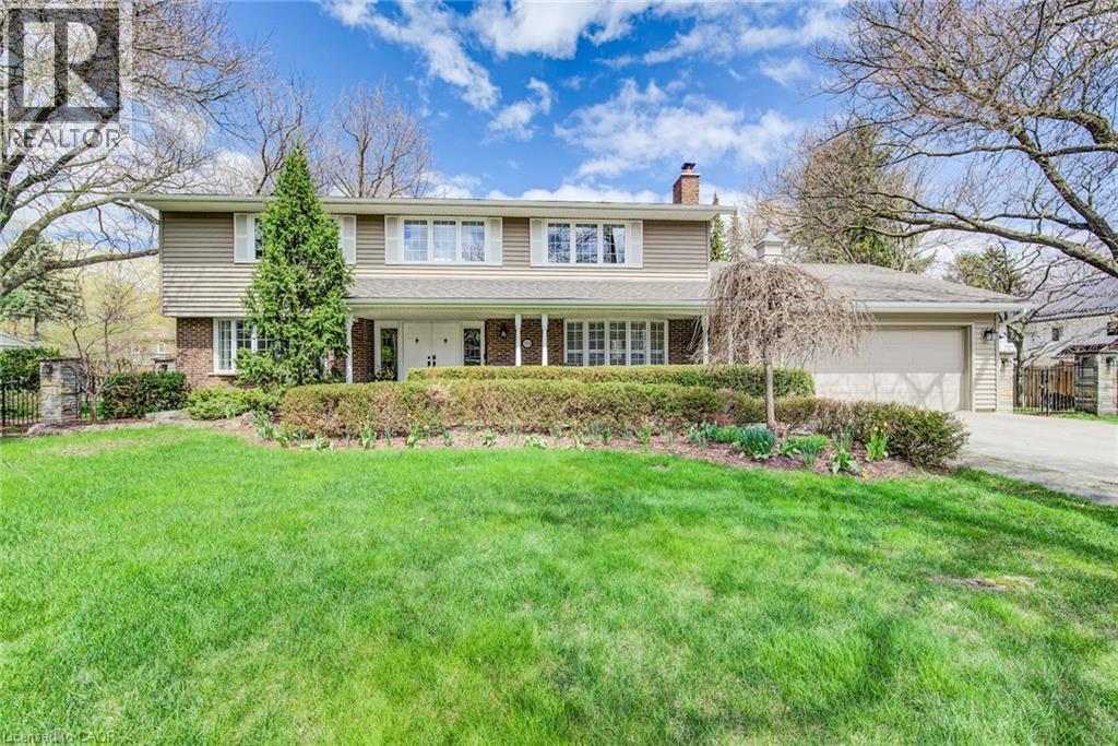 Traditional-style residence featuring a two-story design with brick and siding facade, an integrated two-car garage, a covered front porch, a cultivated front garden bed, and a spacious front lawn - 514 Colonial Drive, Waterloo, ON - Outdoor With Facade