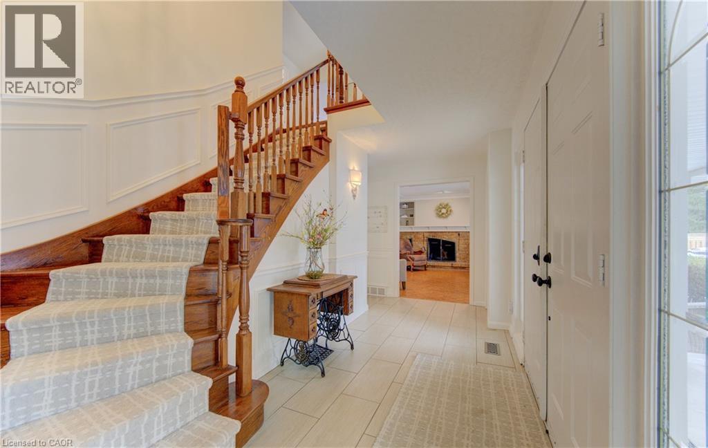 Grand entryway featuring a hardwood staircase with carpet runner, white wainscoting, and tile flooring - 514 Colonial Drive, Waterloo, ON - Indoor Photo Showing Other Room