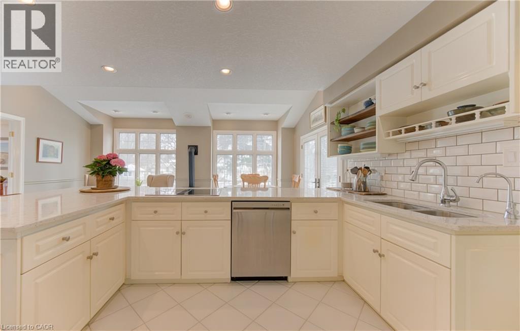 Bright kitchen featuring white cabinetry, light-toned countertops, a stainless steel dishwasher, and a subway tile backsplash - 514 Colonial Drive, Waterloo, ON - Indoor Photo Showing Kitchen With Double Sink