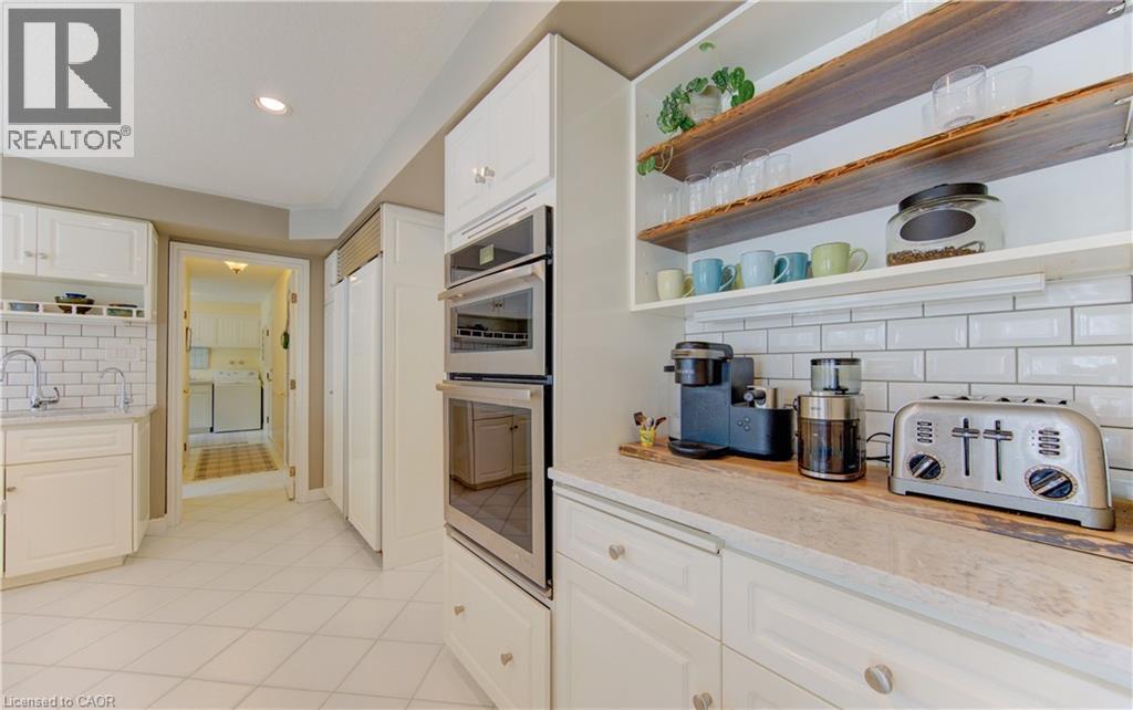White shaker cabinetry, stainless steel double wall ovens, built-in refrigerator panel, light-toned countertop, and subway tile backsplash - 514 Colonial Drive, Waterloo, ON - Indoor Photo Showing Kitchen