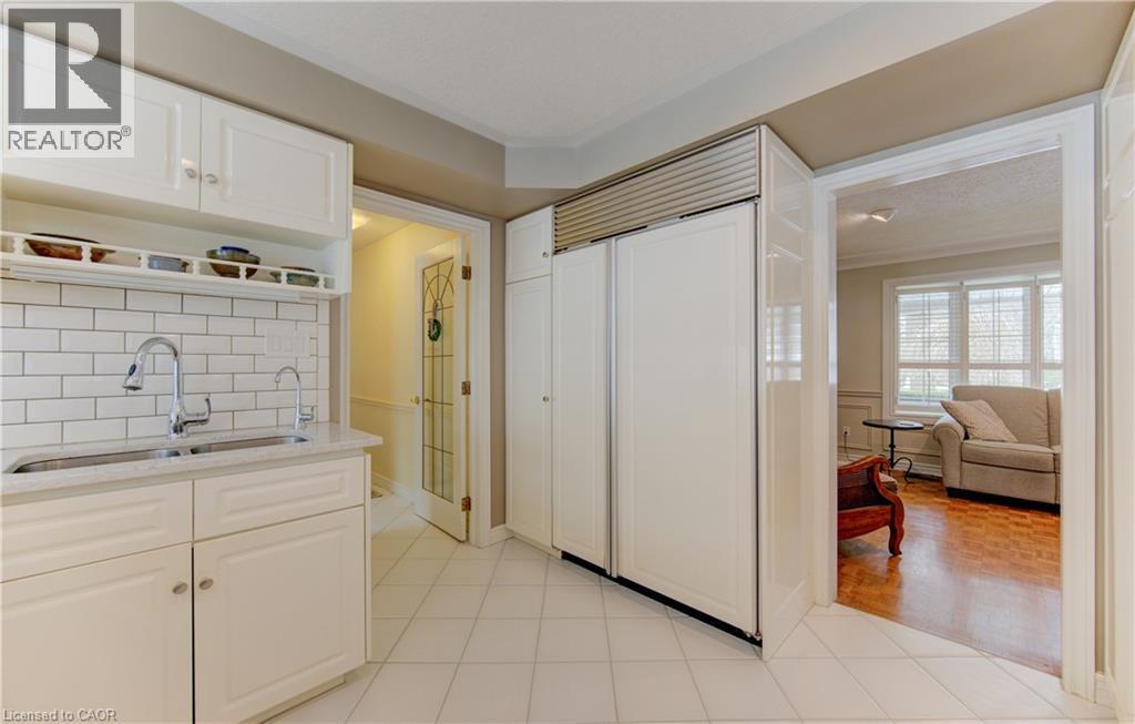 Kitchen featuring white cabinetry, subway tile backsplash, and a double-door paneled refrigerator - 514 Colonial Drive, Waterloo, ON - Indoor Photo Showing Kitchen With Double Sink