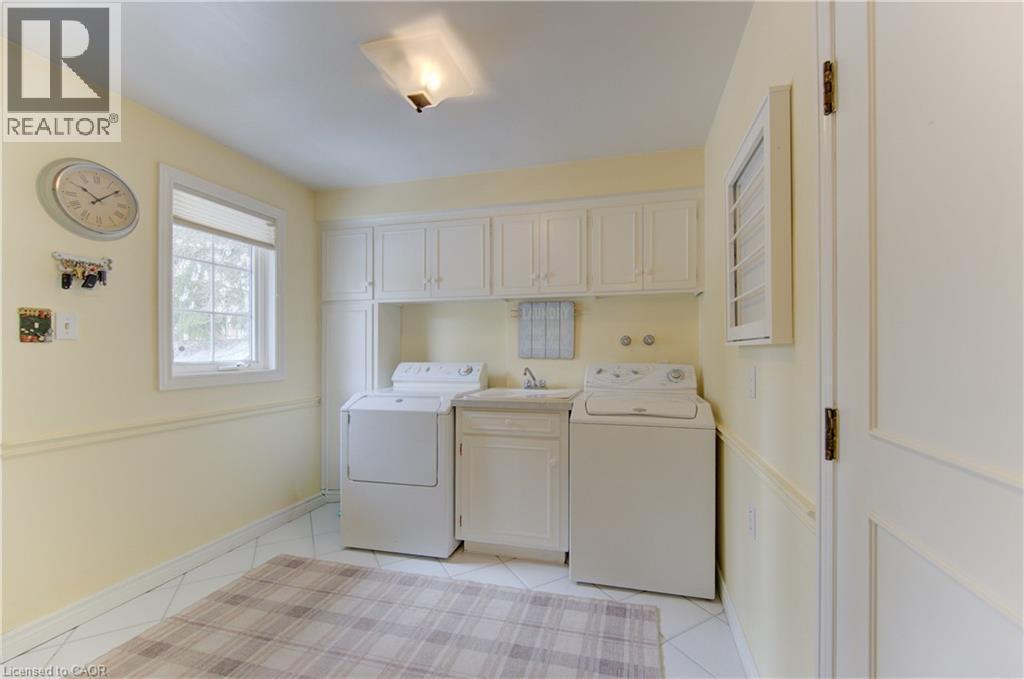 Laundry area featuring white cabinetry, a built-in utility sink, and tile flooring - 514 Colonial Drive, Waterloo, ON - Indoor Photo Showing Laundry Room