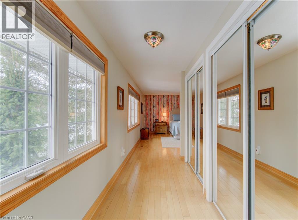Hallway featuring light wood-finish flooring, multiple windows with wood trim, and mirrored sliding closet doors - 514 Colonial Drive, Waterloo, ON - Indoor Photo Showing Other Room