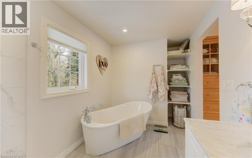 Freestanding soaking tub with chrome fixtures, set against light gray tile flooring - 514 Colonial Drive, Waterloo, ON - Indoor Photo Showing Bathroom