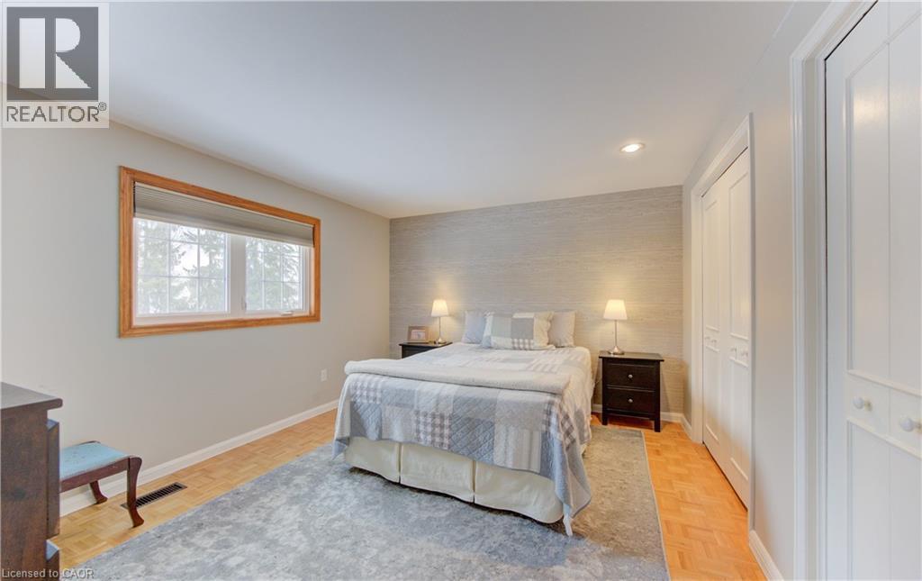 Bedroom featuring wood-finish flooring, a neutral color palette, and built-in closet doors with decorative paneling - 514 Colonial Drive, Waterloo, ON - Indoor Photo Showing Bedroom