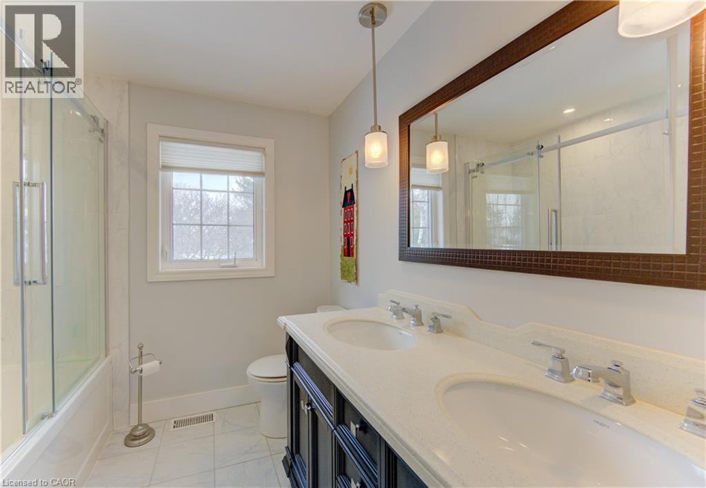 Bathroom featuring a double vanity with integrated sinks, a large framed mirror, and pendant lighting - 514 Colonial Drive, Waterloo, ON - Indoor Photo Showing Bathroom