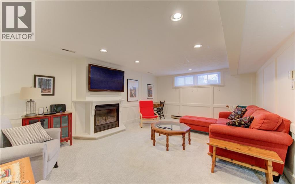 Carpeted recreation room featuring a corner fireplace with a mounted television above - 514 Colonial Drive, Waterloo, ON - Indoor With Fireplace