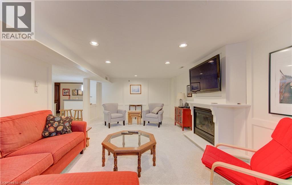 Recessed lighting illuminates this room featuring white walls, carpeting, a built-in fireplace, and a partial view of a bar area with wood-finish details - 514 Colonial Drive, Waterloo, ON - Indoor Photo Showing Living Room With Fireplace