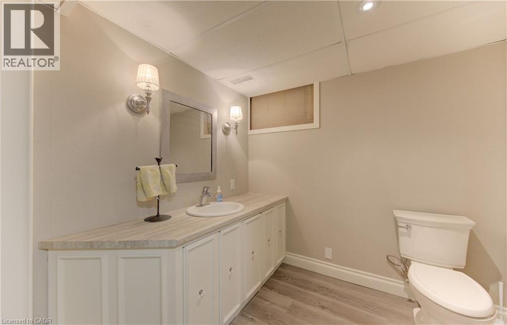 Bathroom featuring a white vanity with a stone-look countertop, undermount sink, and wall-mounted sconces - 514 Colonial Drive, Waterloo, ON - Indoor Photo Showing Bathroom