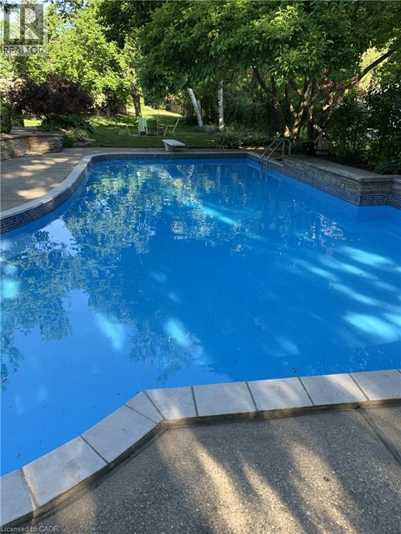 In-ground swimming pool featuring a tiled waterline and surrounding aggregate concrete decking - 514 Colonial Drive, Waterloo, ON - Outdoor With In Ground Pool With Backyard