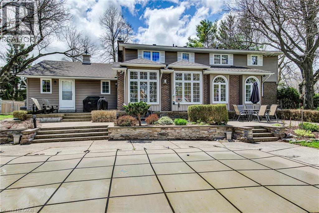 Rear exterior featuring a covered pool area, tiered hardscaping, and multiple access points - 514 Colonial Drive, Waterloo, ON - Outdoor With Facade