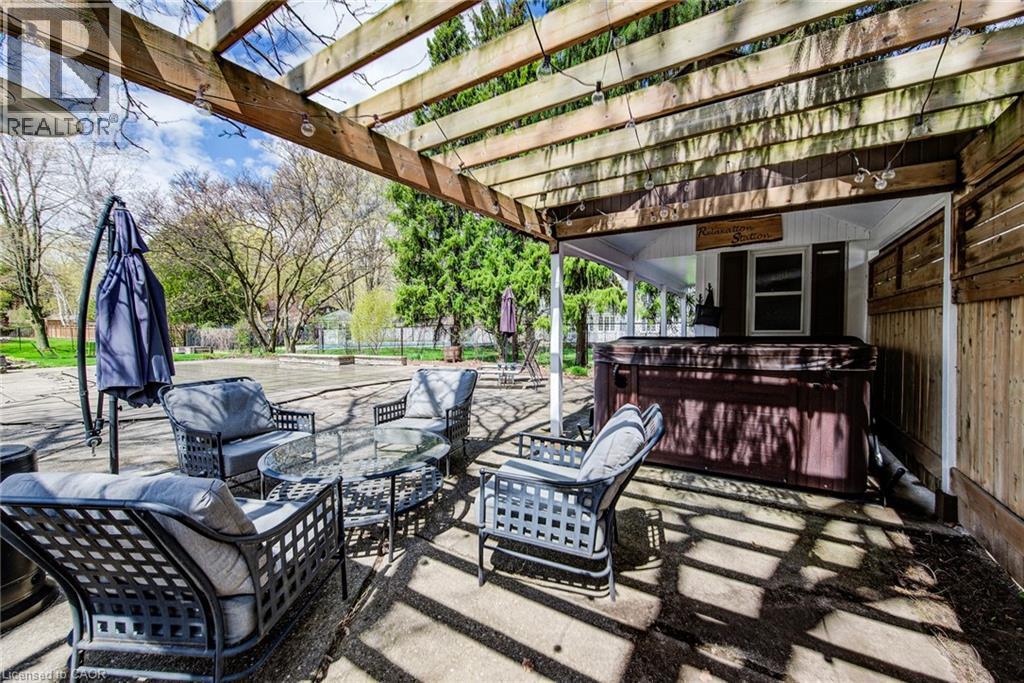 Outdoor living area featuring a wooden pergola, string lighting, concrete patio, and a built-in spa - 514 Colonial Drive, Waterloo, ON - Outdoor With Deck Patio Veranda