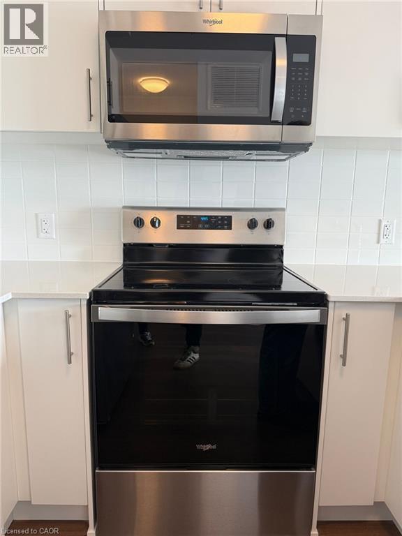 Kitchen with white cabinetry, light countertops, stainless steel appliances, and decorative backsplash - 1000 Lackner Place Unit# 401, Kitchener, ON - Indoor Photo Showing Kitchen