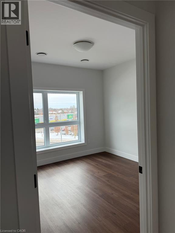 Spare room featuring baseboards and dark wood-style flooring - 1000 Lackner Place Unit# 401, Kitchener, ON - Indoor Photo Showing Other Room