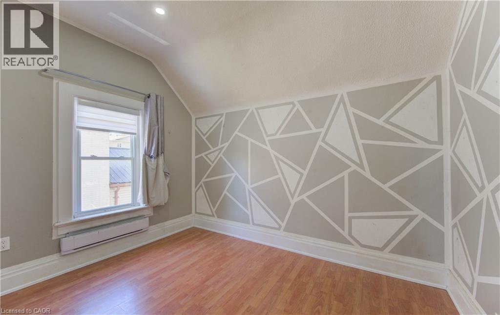 Unfurnished room with light wood-style flooring, baseboard heating, and lofted ceiling - 138 Courtland Avenue E, Kitchener, ON - Indoor Photo Showing Other Room
