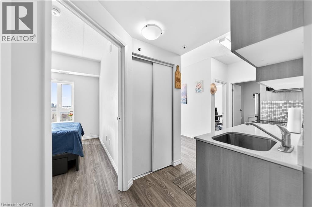 Compact kitchen featuring wood-finish cabinetry, a stainless steel undermount sink, and a light-colored countertop - 246 Lester Street Unit# Ph-03, Waterloo, ON - Indoor Photo Showing Kitchen