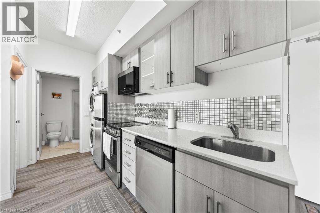 Kitchen featuring wood-finish cabinetry, stainless steel appliances, a square tile backsplash, and a white countertop with an undermount sink - 246 Lester Street Unit# Ph-03, Waterloo, ON - Indoor Photo Showing Kitchen With Upgraded Kitchen