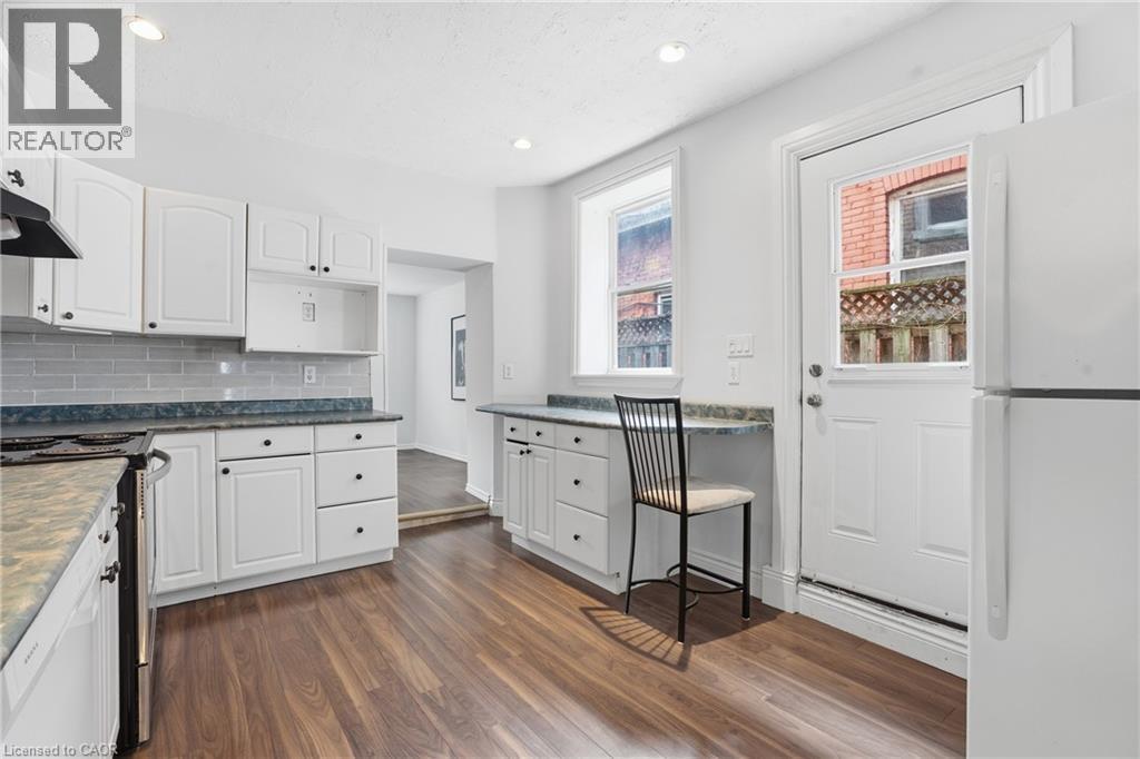 Kitchen featuring white cabinetry, wood-finish flooring, recessed lighting, subway tile backsplash, and an exterior door with integrated window - 137 Market Street, Hamilton, ON - Indoor Photo Showing Kitchen