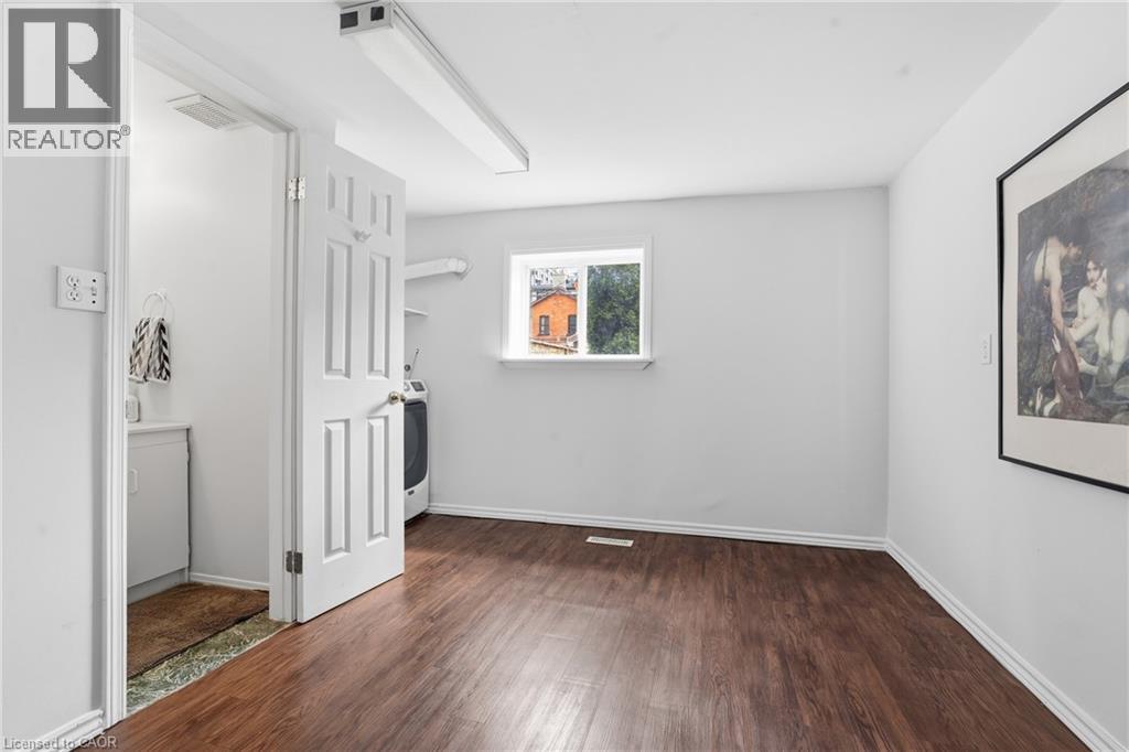 Spacious room featuring wood-finish flooring, white baseboards, and a window providing natural light - 137 Market Street, Hamilton, ON - Indoor Photo Showing Other Room