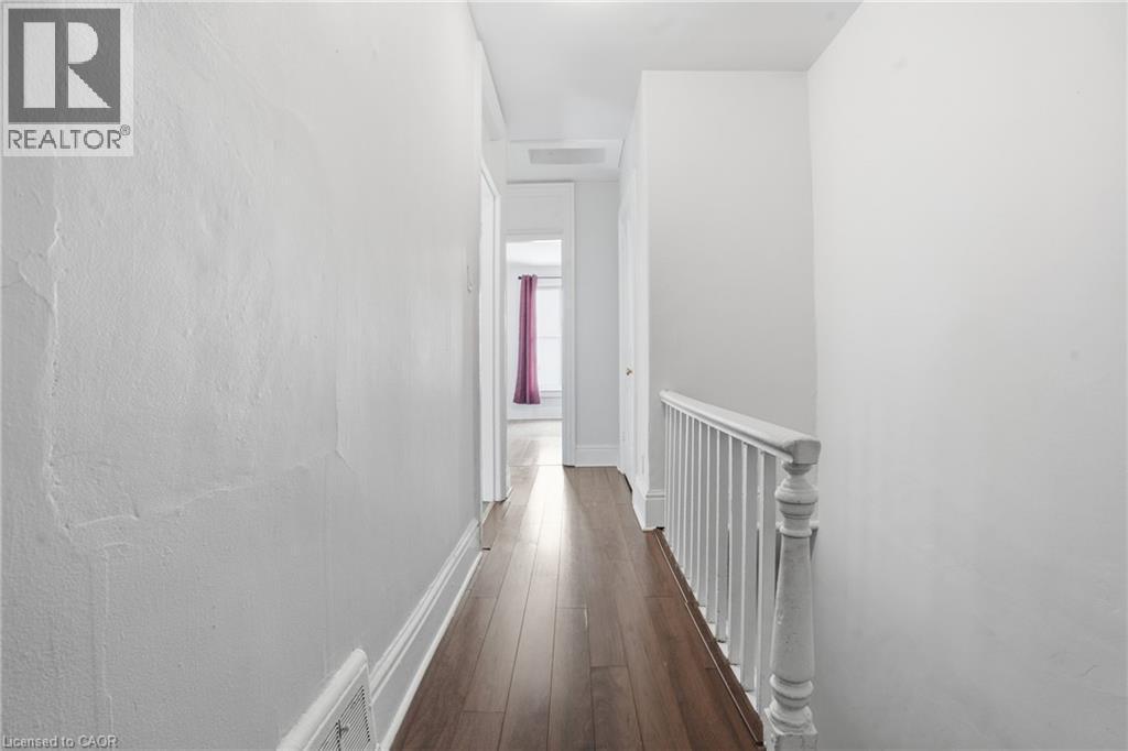 Wood-finish flooring throughout a hallway with white painted walls and baseboards - 137 Market Street, Hamilton, ON - Indoor Photo Showing Other Room