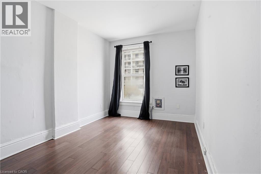 Hardwood-finish flooring highlights this room with white walls and baseboards - 137 Market Street, Hamilton, ON - Indoor Photo Showing Other Room