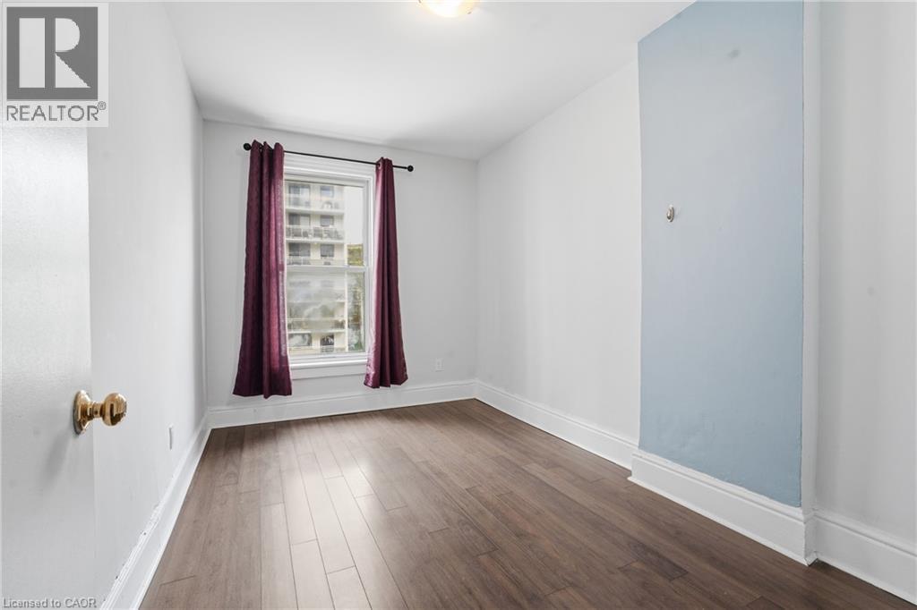 Bright room featuring wood-finish flooring, a double-hung window, and a light fixture - 137 Market Street, Hamilton, ON - Indoor Photo Showing Other Room