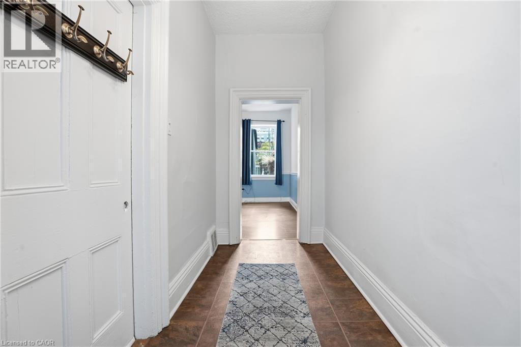 Entryway featuring a paneled door, dark bronze coat rack, and white baseboards - 137 Market Street, Hamilton, ON - Indoor Photo Showing Other Room