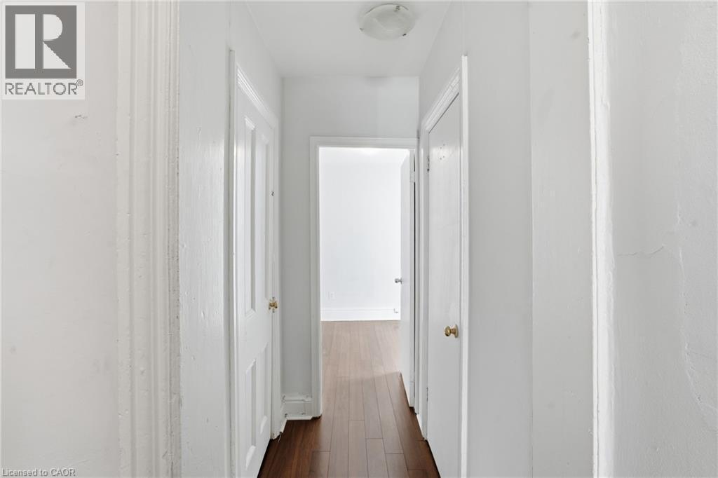 Hallway with wood-finish flooring, white walls, and white paneled doors with brass hardware - 137 Market Street, Hamilton, ON - Indoor Photo Showing Other Room