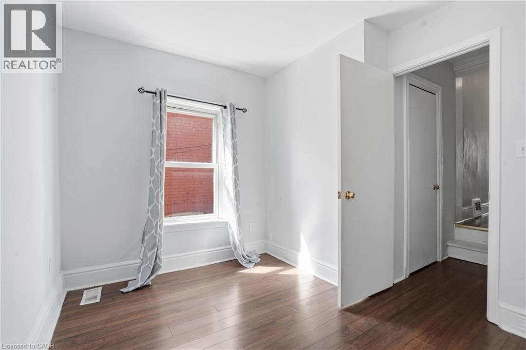 Room with wood-finish flooring, white baseboards, and light gray walls - 137 Market Street, Hamilton, ON - Indoor Photo Showing Other Room