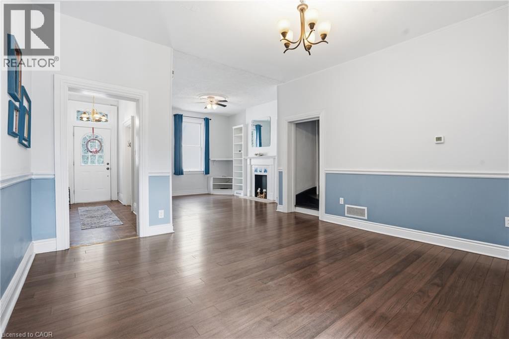 Spacious room featuring wood-finish flooring, wainscoting, and an antique brass chandelier - 137 Market Street, Hamilton, ON - Indoor Photo Showing Other Room
