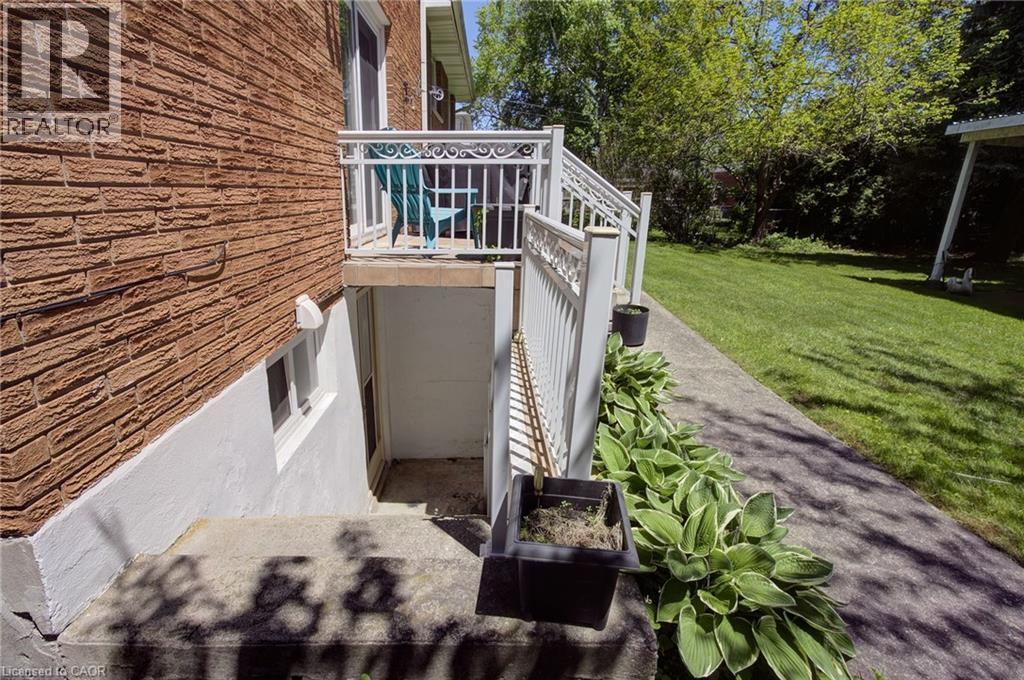 Exterior featuring a brick facade with a white lower foundation, a concrete patio, a private exterior entrance, and a white metal railing - 2344 Brinell Avenue, Burlington, ON - Outdoor
