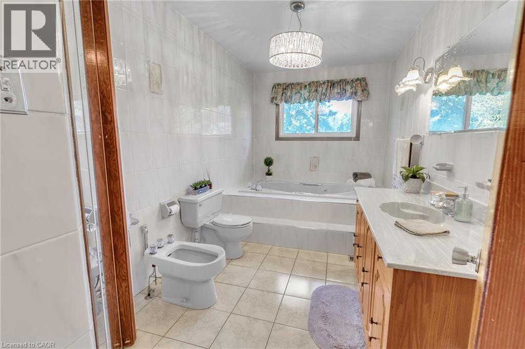 Full bathroom featuring a built-in jetted tub, dual-sink vanity with a light-toned countertop, and tiled flooring - 2344 Brinell Avenue, Burlington, ON - Indoor Photo Showing Bathroom