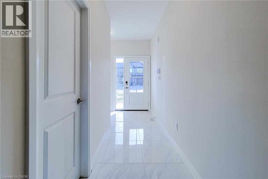 Bright entryway featuring large format polished tile flooring, a white paneled door with chrome hardware, and a glass-paneled front door - 111 Alicia Crescent, Thorold, ON