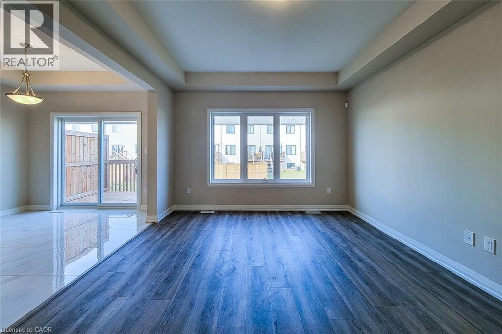 Spacious interior featuring a combination of wood-finish flooring and reflective tile, a tray ceiling, and a large window providing ample natural light - 111 Alicia Crescent, Thorold, ON