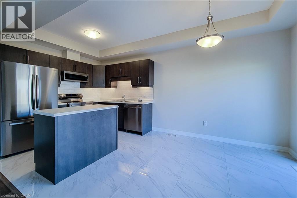 Kitchen featuring dark wood-finish cabinetry, stainless steel appliances, and a central island with a light-toned countertop - 111 Alicia Crescent, Thorold, ON