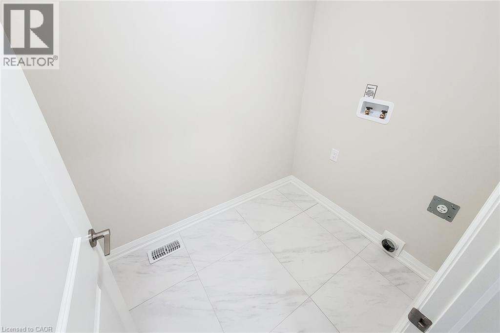 Dedicated utility room featuring white tile flooring, neutral wall paint, and white baseboards - 111 Alicia Crescent, Thorold, ON