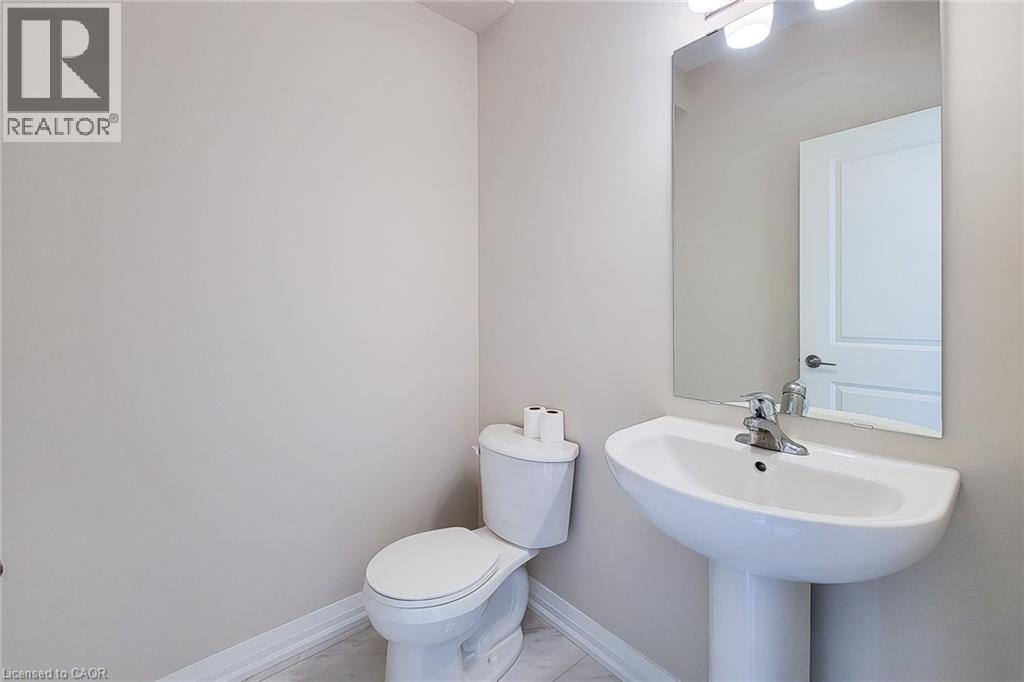 Pedestal sink with chrome faucet, wall-mounted mirror, and overhead vanity lighting - 111 Alicia Crescent, Thorold, ON