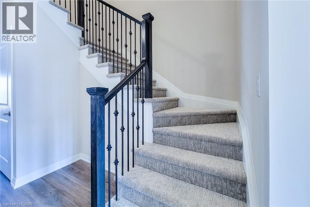 Carpeted staircase featuring black wrought iron balusters and a dark wood newel post - 111 Alicia Crescent, Thorold, ON
