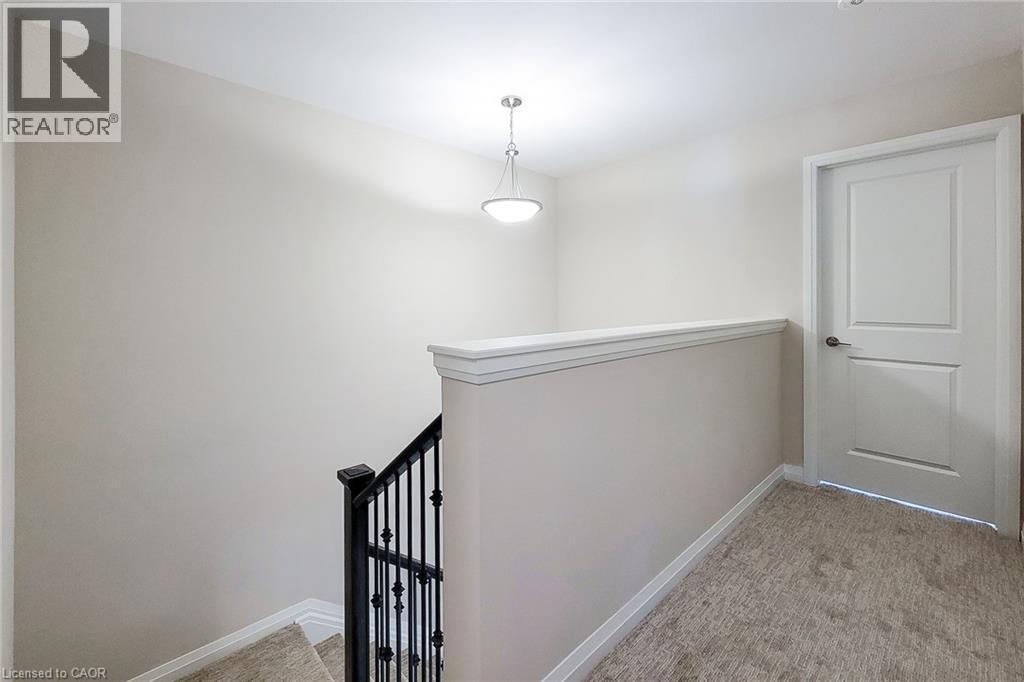 Upper landing featuring plush carpeting, a suspended light fixture, and a white panel door - 111 Alicia Crescent, Thorold, ON