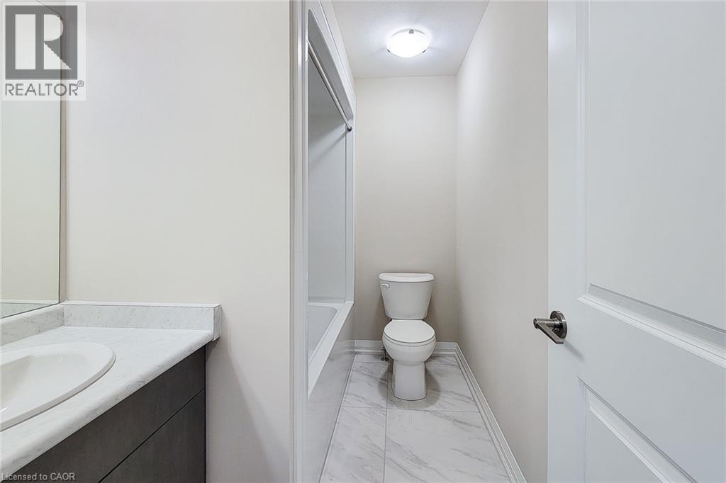Bathroom featuring a vanity with an integrated sink and light-toned countertop, a bathtub with a shower surround, a toilet, and light-toned floor tiling - 111 Alicia Crescent, Thorold, ON