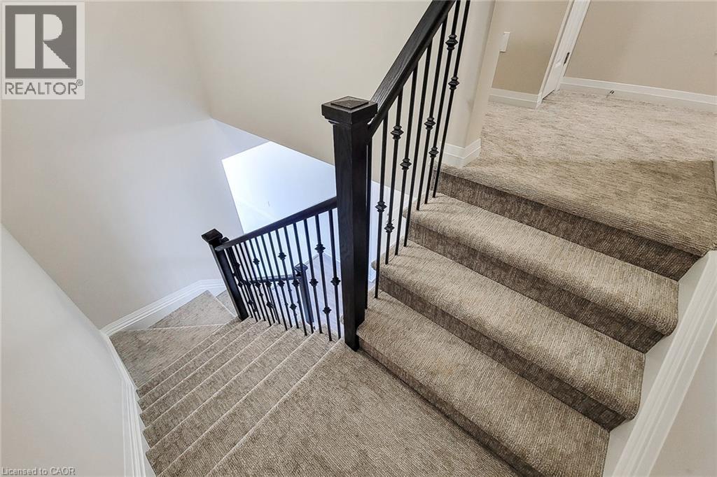 Staircase featuring dark wrought iron balusters and newel posts with light-colored, patterned carpeting - 111 Alicia Crescent, Thorold, ON