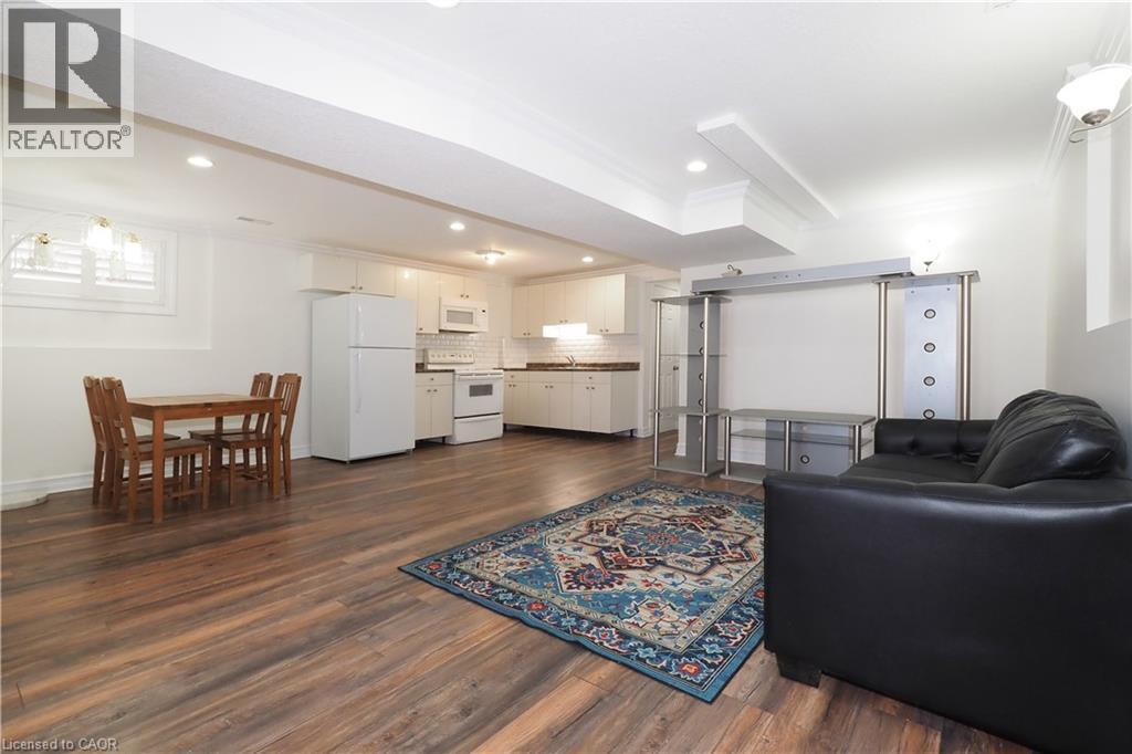 Open-concept living space featuring wood-finish flooring, recessed lighting, and a kitchen with white cabinetry and appliances - 67 Hollyridge Crescent Unit# Lower, Kitchener, ON - Indoor Photo Showing Living Room