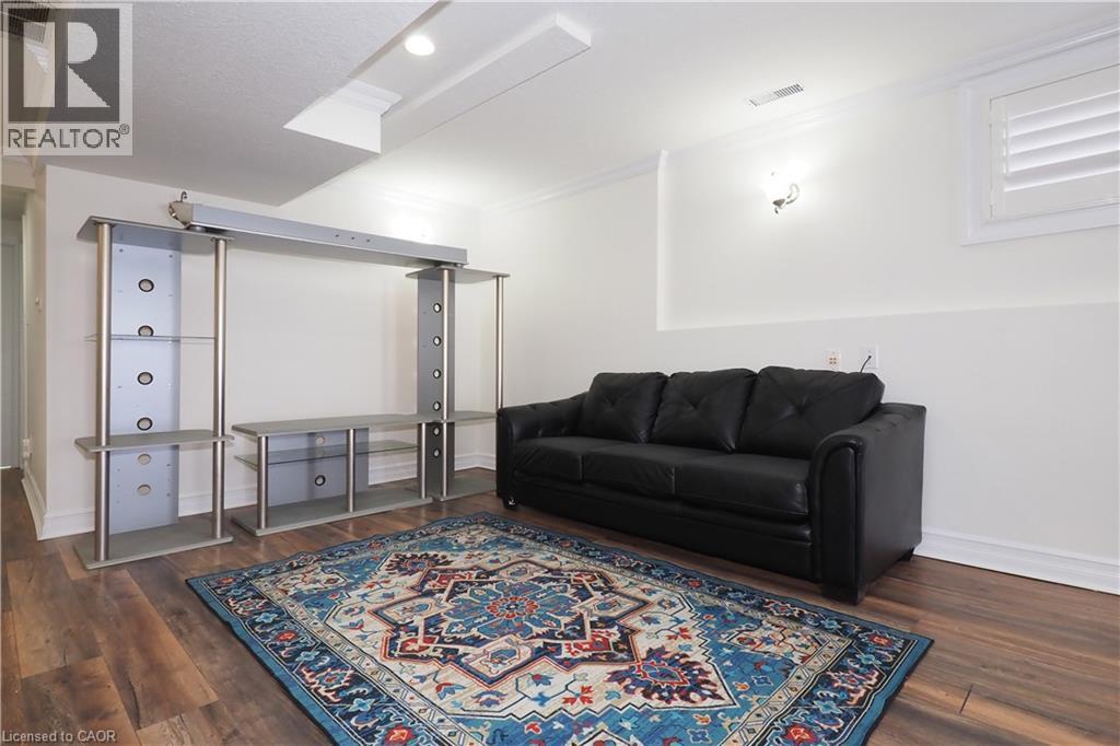 Spacious room featuring wood-finish flooring, white walls, and crown molding - 67 Hollyridge Crescent Unit# Lower, Kitchener, ON - Indoor