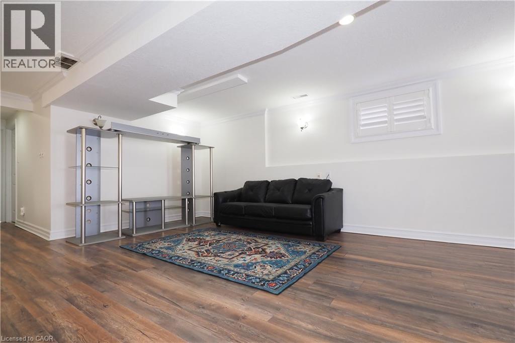 Spacious lower level featuring wood-finish flooring, recessed lighting, crown molding, and a window with white louvered shutters - 67 Hollyridge Crescent Unit# Lower, Kitchener, ON - Indoor