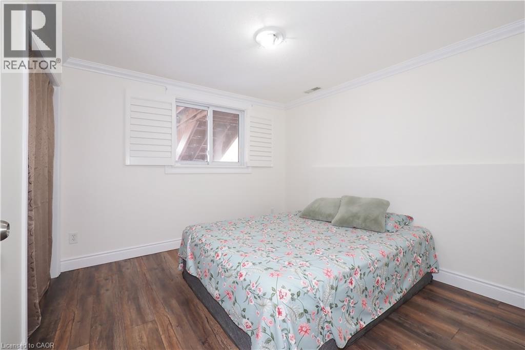 Room featuring wood-finish flooring, crisp white walls, crown molding, and a window with white louvered shutters - 67 Hollyridge Crescent Unit# Lower, Kitchener, ON - Indoor Photo Showing Bedroom