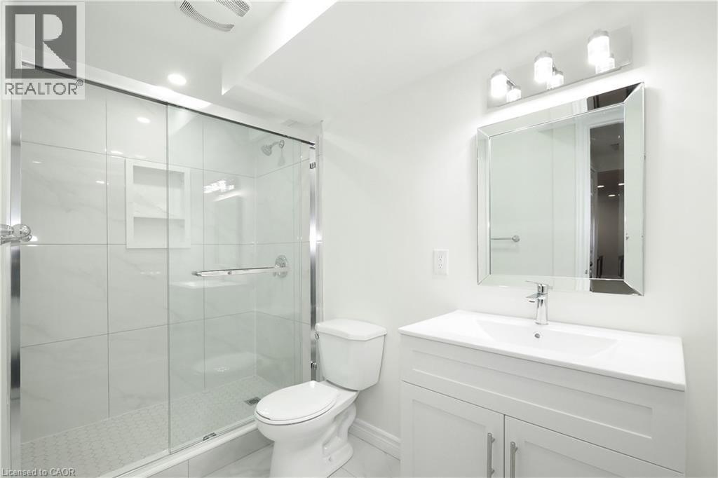 Bathroom featuring a glass-enclosed shower with tile surround, a built-in shower niche, and a white vanity with integrated sink - 67 Hollyridge Crescent Unit# Lower, Kitchener, ON - Indoor Photo Showing Bathroom